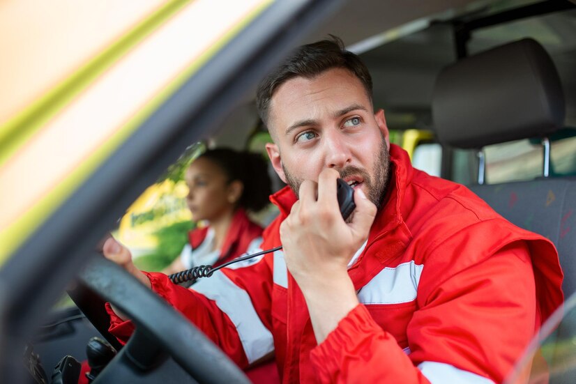 handsome-young-male-paramedic-talking-by-portable-radio-while-sitting-ambulance_657921-1517